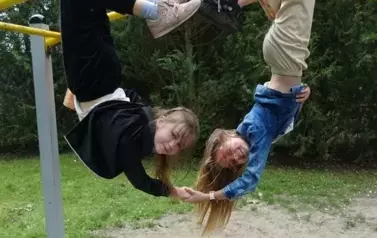 dwie dziewczynki zwisające z drabinek głową w d&oacute;ł 
