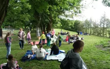 uczniowie siedzący na rozłożonych kocach
