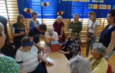 Seniorzy biorący udział w zabawie "Zgadnij co jest w kartoniku"