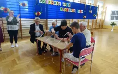 Seniorzy wraz z uczniami biorący udział w zabawie sprawnościowej z butelkami