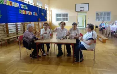 Seniorki biorące udział w zabawie sprawnościowej z butelkami 