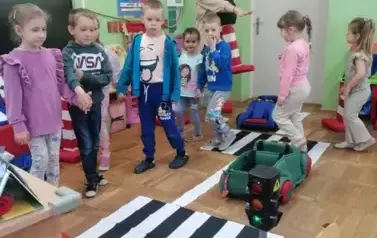 przedszkolaki uczą się jak prawidłowo przechodzić przez pasy bezpieczeństwa