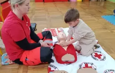 chłopiec ćwiczący na fantomie uciski klatki piersiowej