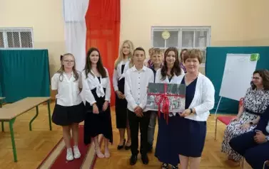 Pani Dyrektor wraz z samorządem uczniowskim, trzymająca w ręku prezent od społeczności uczniowskiej