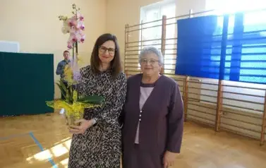 pani dyrektor trzymająca kwiatka doniczkowego, obok emerytowany pracownik szkoły