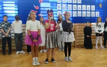 przedstawienie uczni&oacute;w klas IV i V z okazji Dnia Edukacji Narodowej, na pierwszym planie 3 dziewczynki ubrane w barwe stroje