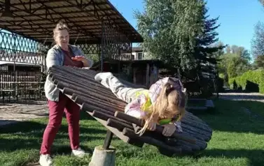 dziewczynka na konstrukcji drewnianej bujająca sie wkoło