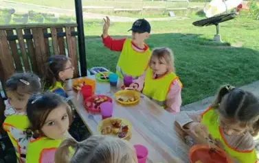 dzieci zajadające kiełbaskę z ogniska