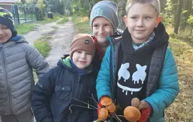 chłopcy prezentujący grzyby, kt&oacute;re znaleźli w lesie