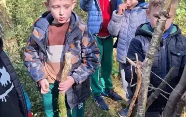 chłopcy przygotowujący się do budowy szałasu z w lesie