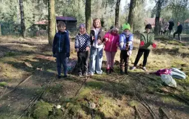 grupa dzieci prezentująca wykonane zadanie w lesie