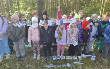 grupa dzieci prezentująca wykonane zadanie w lesie