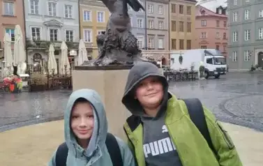 dw&oacute;jka chłopc&oacute;w przed pominkiem wwarszawskiej syrenki