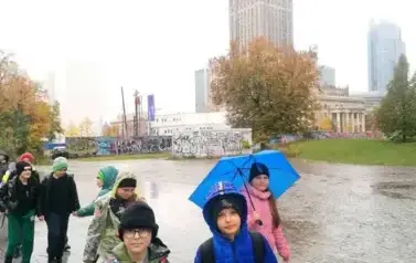 spacerujące dzieci, w tle widac Pałac Kultury i Nauki, pogoda deszczowa
