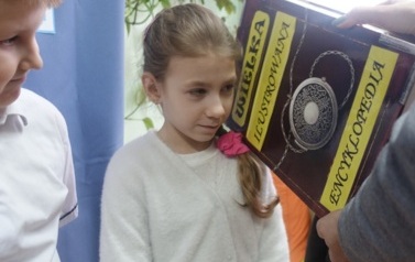 uczennica pasowana książką na czytelnika biblioteki szkolnej