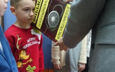 uczeń pasowany książką na czytelnika biblioteki szkolnej