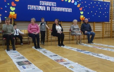 dziadki biorący udział w zabawie z gazetami