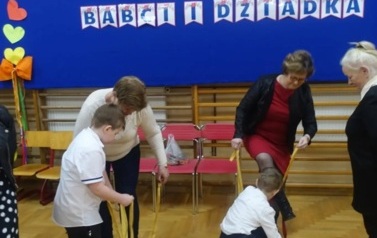 dzieci z dizadkami biorący udział w zabawie z szarfami