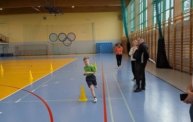 chłopiec biegnący na hali sportowej podczas zawod&oacute;w sportowych