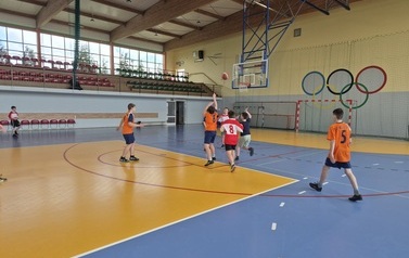 chłopcy grający w koszyk&oacute;wkę na hali sportowej