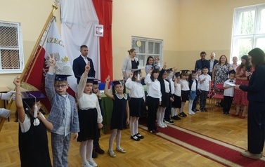 pierwszoklasiści z podniesionymi palcami na ślubowaniu na ucznia