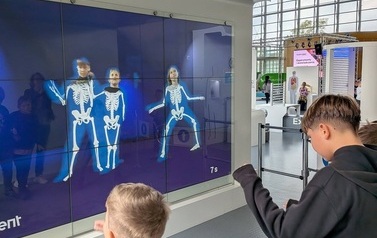 chłopcy przed tablicą interaktywną a na niej ich twarze połączone ze szkieletami