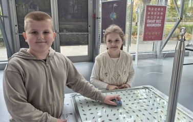 Uczniowie poznają właściwości magnetyzmu, wykonując doświadczenie przy interaktywnej ekspozycji z magnesami na wystawie naukowej.