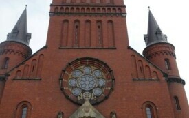 uczniowie na tle neoromańskiego kościoła