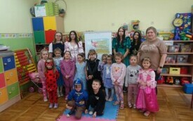 Dzieci z oddziału przedszkolnego pozują na tle napisu "Dzień ostaci z bajek"