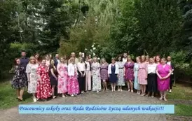 Pracownicy szkoły oraz Rada Rodzic&oacute;w na tle zieleni