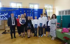 absolwenci trzymający świadectwa wraz z rodzicami, wychowawcą, Panią Dyrektor i Panem Burmistrzem