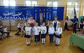 dzieci kończące oddział przedszkolny z dyplomami wraz z wychowawcą, Panią dyrektor i Panem Burmistrzem