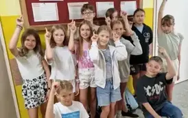 uczniowie 5 klasy wskazujący na gazetkę szkolną