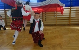 uczniowie klasy I przebrani tańczą "Krakowiaczka" w tle pozostali uczniowie
