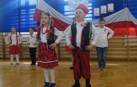 uczniowie klasy I przebrani tańczą "Krakowiaczka" w tle pozostali uczniowie