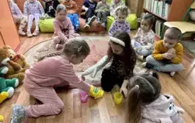 dzieci pr&oacute;bujące złapać patyczki rękawicami kuchennymi