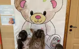 dzieci z przedszkola kolorują wielkiego misia