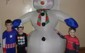 dzieci pozują do zdjęcia z dmuchanym bałwanem 