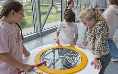 Uczniowie podczas wsp&oacute;lnej zabawy przy interaktywnym labiryncie na wystawie edukacyjnej.