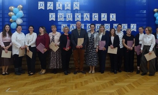 nauczyciele i pracownicy szkoły na tle dekoracji z okazji Dnia Edukacji Narodowej